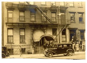 Early automobile outside a brick building with an awning. The awning reads "Jewish Maternity Hospital, 270"